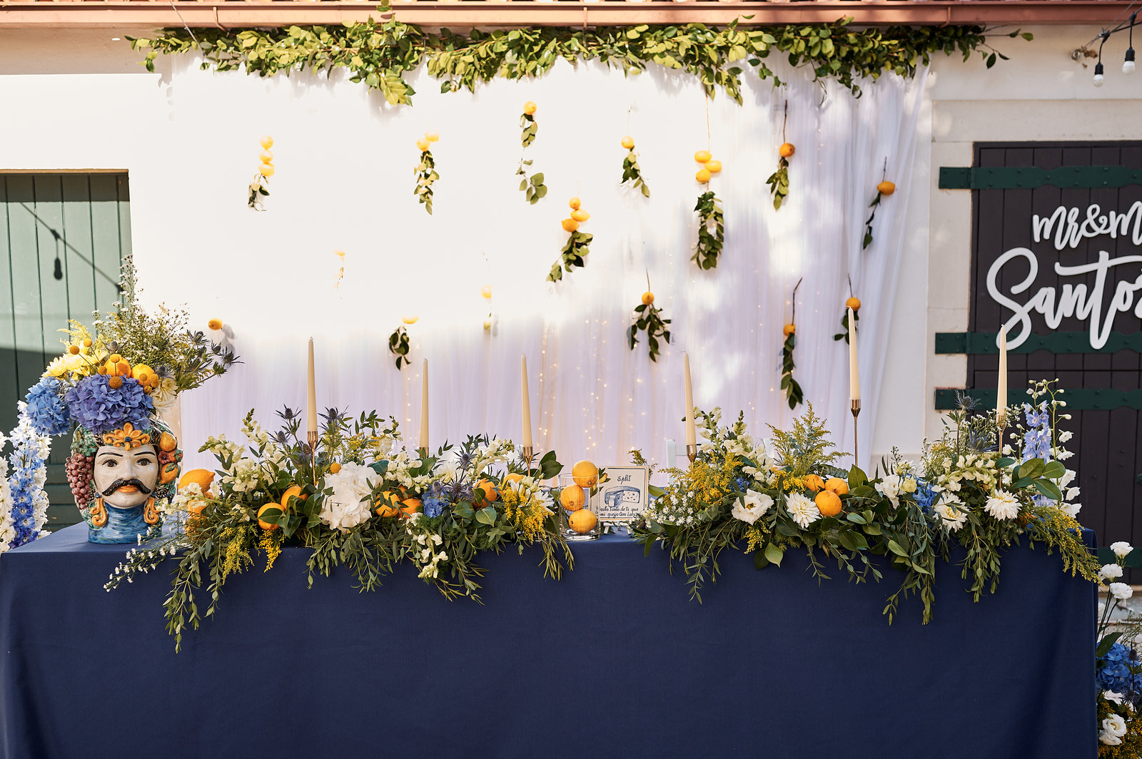 Mesa decorada com limões, flores azuis e brancas e cerâmica tradicional mediterrânica