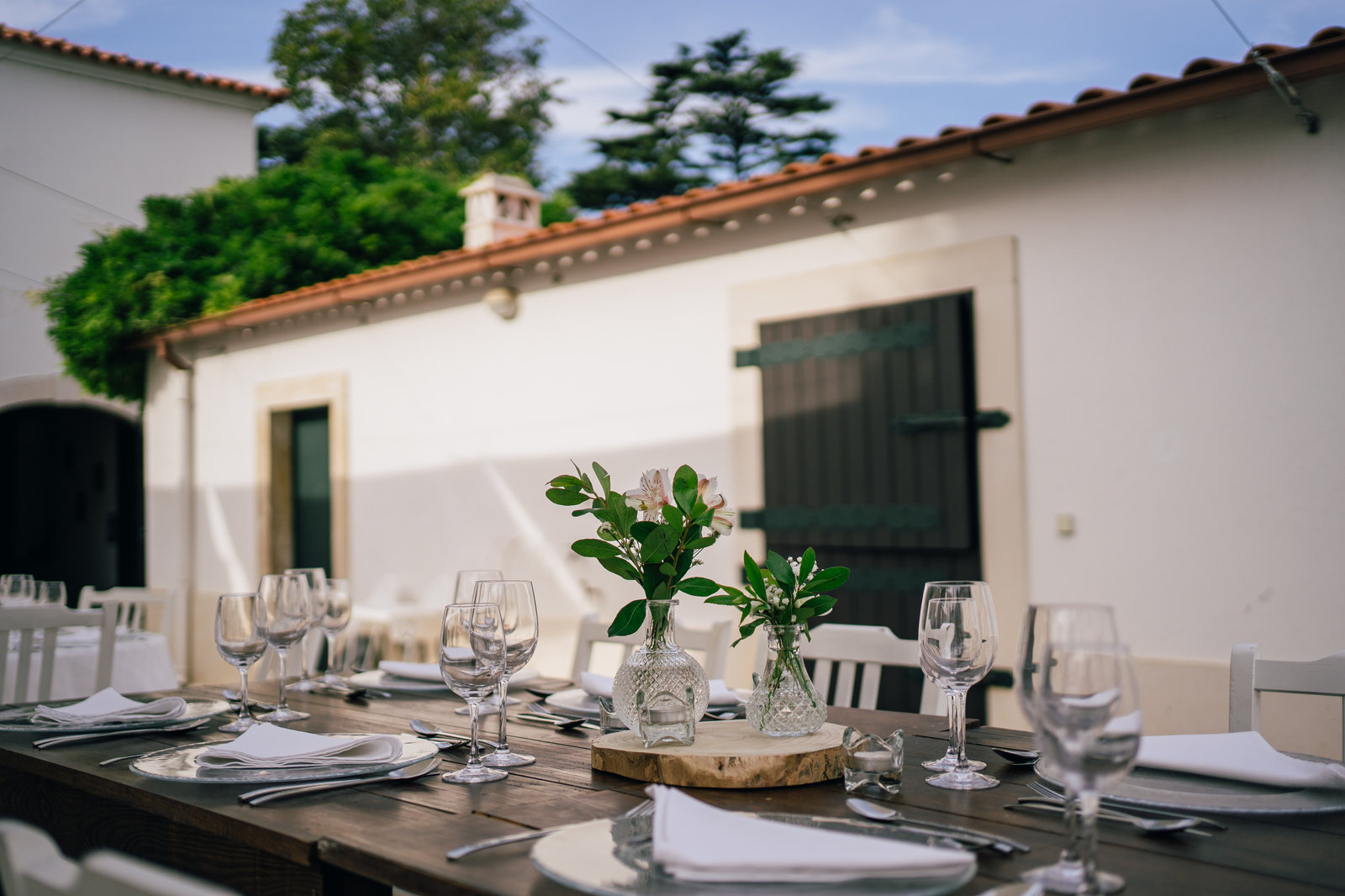 Mesa de jantar preparada ao entardecer no páteo da quinta